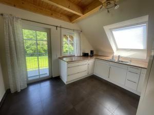 a kitchen with white cabinets and a sink and two windows at Ferienwohnungen Fischbachhof in Sulzbach an der Murr
