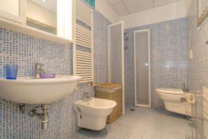 a blue tiled bathroom with a sink and a toilet at Castiglioncello Mare Apartment in Castiglioncello +20 photos
