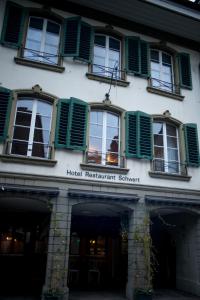 a building with green shuttered windows and a hotel restaurant sign at Hotel Restaurant Schwert Thun in Thun