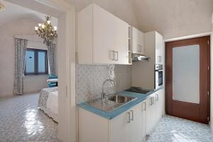 a kitchen with white cabinets and a sink at Dimora elegante in Costa d'Amalfi in Conca dei Marini