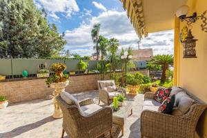 a patio with wicker furniture and a stone wall at Villetta Mare e Monti in Mascali
