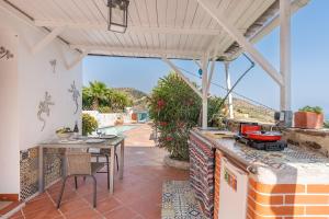 an outdoor patio with a table and a grill at Cortijo La Alamea in Almuñécar