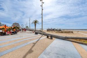 a sidewalk next to the beach with people sitting at Sunny Day in La Grande Motte