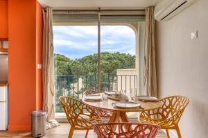 a dining room with a table and chairs and a large window at Sunny Day in La Grande Motte
