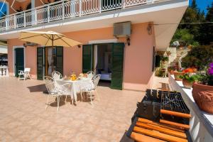 a patio with a table and chairs and an umbrella at Maestro Apartment 2 in Vlachopoulátika