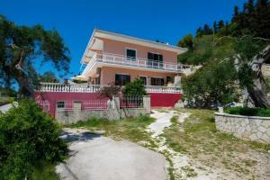 a pink house on the side of a hill at Maestro Apartment 2 in Vlachopoulátika +12 photos