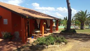 a red building with a table and chairs in a yard at Agriturismo Debbione Maro' in Suvereto