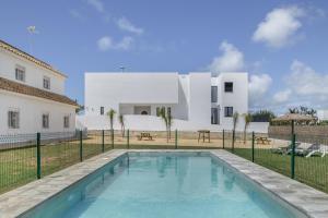 a villa with a swimming pool in front of a house at Complejo Alejandra in Conil de la Frontera