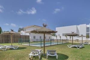 a group of chairs and umbrellas next to a pool at Complejo Alejandra in Conil de la Frontera