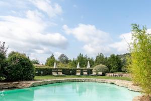 a swimming pool in a yard with chairs and umbrellas at Apartament Monastero in Cortona