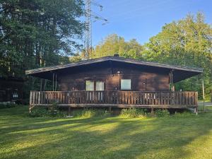 a log cabin with a deck in the grass at Weiherhüttla in Untersteinach