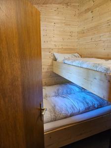 two bunk beds in a wooden room with a door at Weiherhüttla in Untersteinach