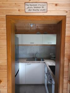a kitchen with white cabinets and a sign above a sink at Weiherhüttla in Untersteinach