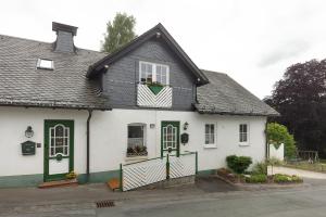 a white house with a black roof and green doors at Chalet Sonnenhügel in Schmallenberg
