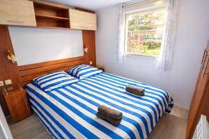 a bedroom with a bed with blue and white stripes at Bungalow Camping 4 étoiles - Mer à pied in Hyères