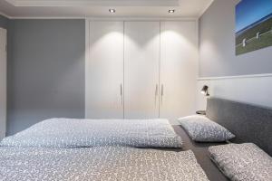 a bedroom with two beds and a white cabinet at Kleine Auszeit in Dagebüll
