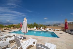 a swimming pool with lounge chairs and an umbrella at Sublime Appart Neuf in Albitreccia