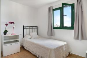 a white bedroom with a bed and a window at San roque in Tinajo
