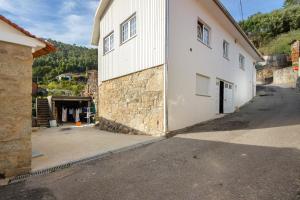 a large white building next to a street at Casa Cimo D'Aldeia in Vila Cova de Perrinho