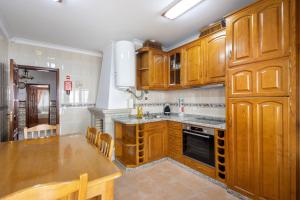 a kitchen with wooden cabinets and a wooden table at Casa Cimo D'Aldeia in Vila Cova de Perrinho