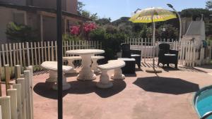 a patio with tables and chairs and an umbrella at Casa Nessi- Stanze in Platamona