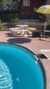 a swimming pool with a picnic table and an umbrella at Casa Nessi- Stanze in Platamona