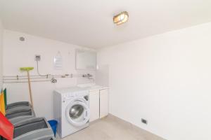 a laundry room with a washing machine and a chair at San Teodoro Villa Ambra Costa Caddu in San Teodoro