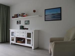 a living room with a white cabinet and a chair at Ferienwohnung Möhneblick in Möhnesee