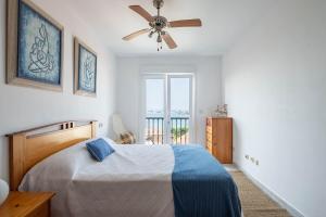 a bedroom with a bed and a ceiling fan at Primera línea de playa Cabo Cruz in Boiro