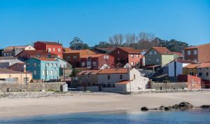a group of houses on a hill next to the beach at Primera línea de playa Cabo Cruz in Boiro