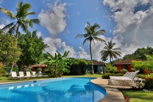 a swimming pool with lounge chairs and palm trees at Hotel Bahia Esmeralda in Potrero