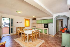 a kitchen with green cabinets and a table and chairs at Appartamento Paguro in Cala Liberotto