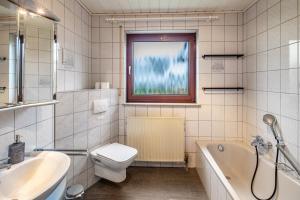 a bathroom with a toilet and a tub and a sink at Am Twistesee 1 Souterraint in Wetterburg +16 photos