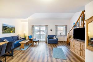 a living room with a blue couch and a tv at Fewo Brünnstein - Zimmer 50 in Oberaudorf