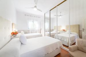 a white bedroom with two beds and a mirror at Cortijo Indalo in Pechina +15 photos