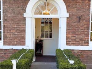 a white door on a brick building with bushes at Corse Lawn House Hotel in Corse
