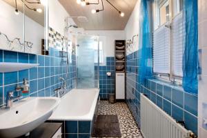 a blue tiled bathroom with a sink and a tub at Ferienwohnung Sink in Staufen im Breisgau +19 photos