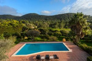 a swimming pool with chairs and mountains in the background at Can Lluc in Nuestra Señora de Jesus