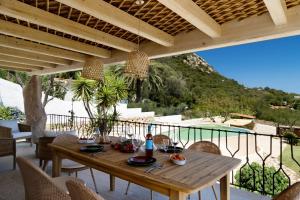 a wooden table on a patio with a view of a pool at Villa Amata in Arzachena