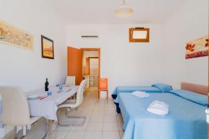 a room with two beds and a table and a dining room at La casetta 461 in Torre San Giovanni Ugento