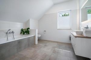 a white bathroom with a tub and a sink at Seeglück 1 am Tollensesee in Groß Nemerow +29 photos