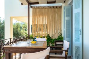 a porch with a table and chairs on a balcony at Afroksilia Villa Triantafilo in Lefkada