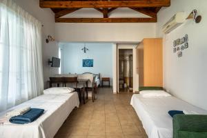 a room with three beds and a dining room at Afroksilia Villa Triantafilo in Lefkada
