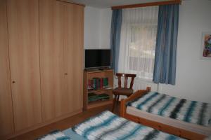 a bedroom with two beds and a tv and a chair at Ferienwohnung Mark in Biberwier
