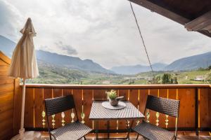 a table and chairs on a balcony with a view of mountains at Sankt Corbinian Apartement 4 in Caines