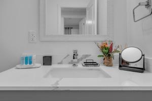 a white bathroom sink with a mirror and flowers at Poolside Paradise minutes away from the Falls in Thorold