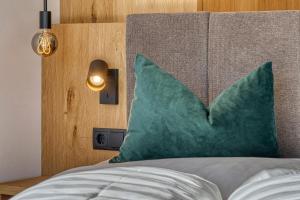 a bed with a green pillow and a wooden headboard at Chalet Schlossberg Schlern in Nova Ponente