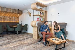 a man and a woman sitting in chairs in a room at Chalet Schlossberg Schlern in Nova Ponente +17 photos