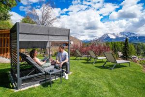 two people sitting in chairs in the grass at Chalet Schlossberg Schlern in Nova Ponente