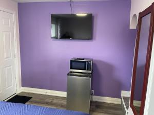 a purple wall with a tv on top of a refrigerator at Oshawa Inn Motel in Oshawa